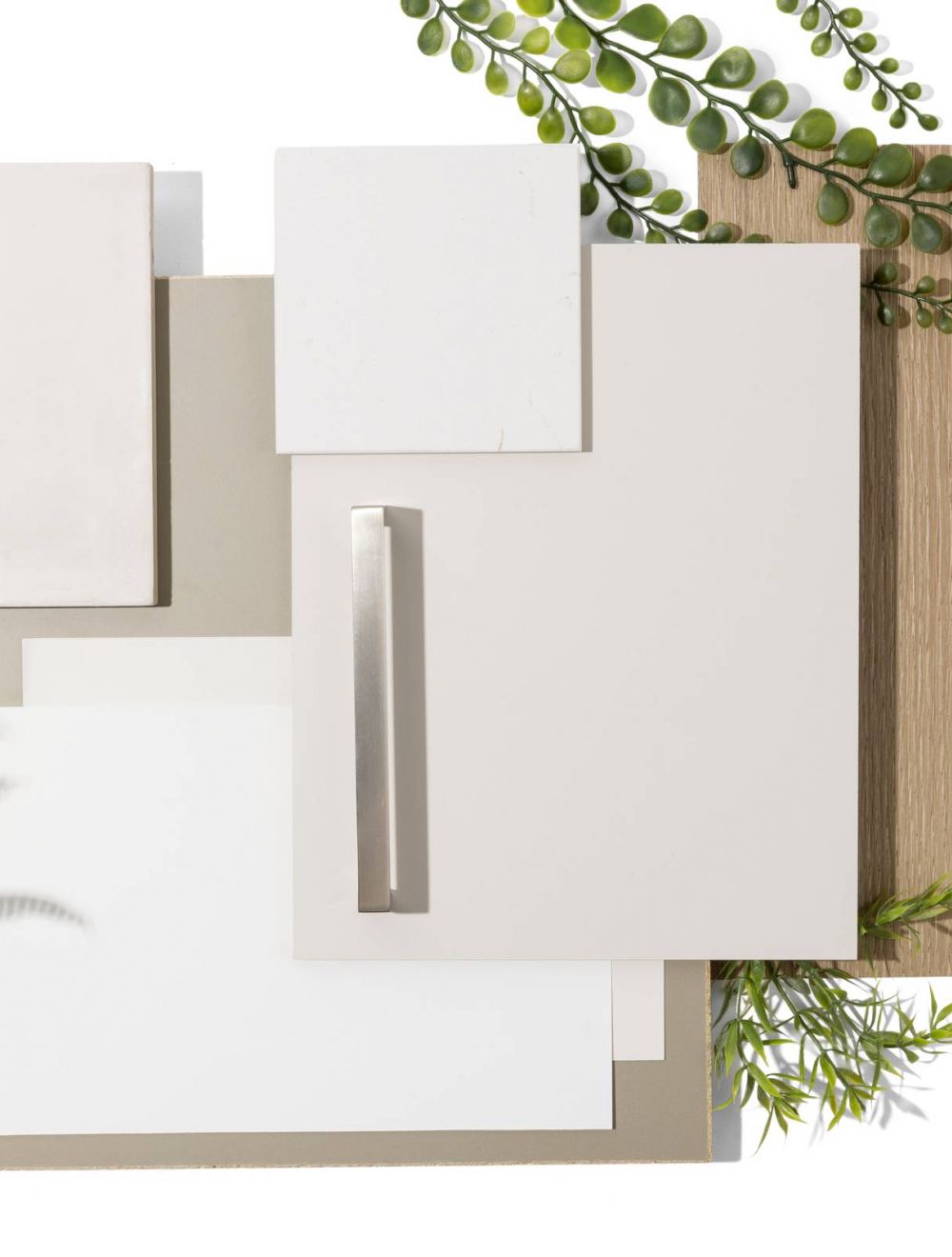 Neutral-toned material samples with white, beige, and tan swatches, metal handle, wood texture, and green leaves.